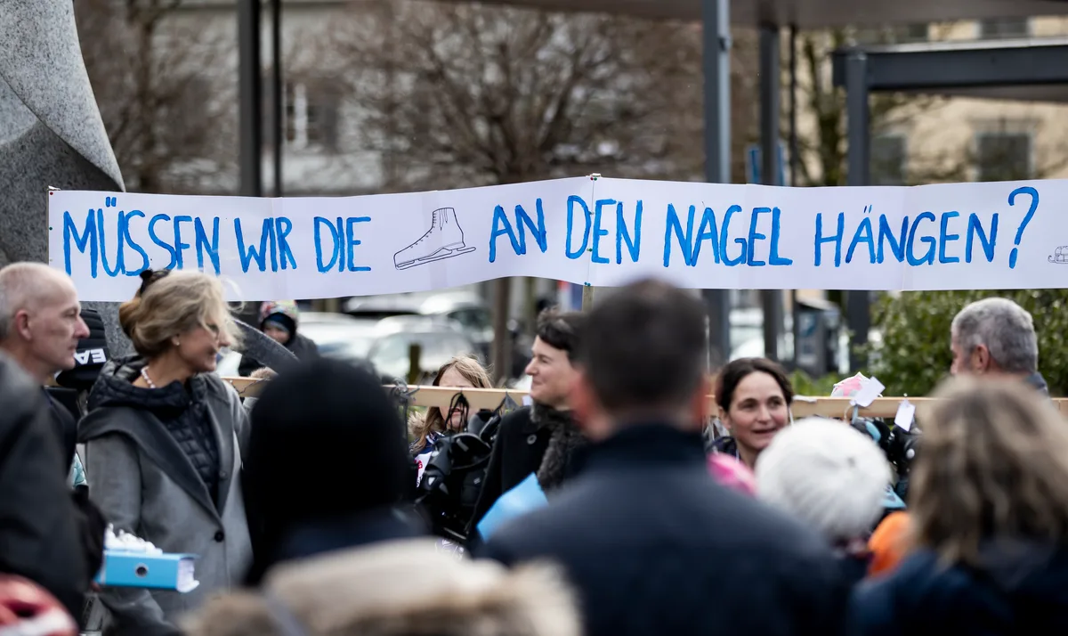 Viele Menschen und ein Transparent mit den Worten: «Müssen wir die Schlittschuhe an den Nagel hängen?» 